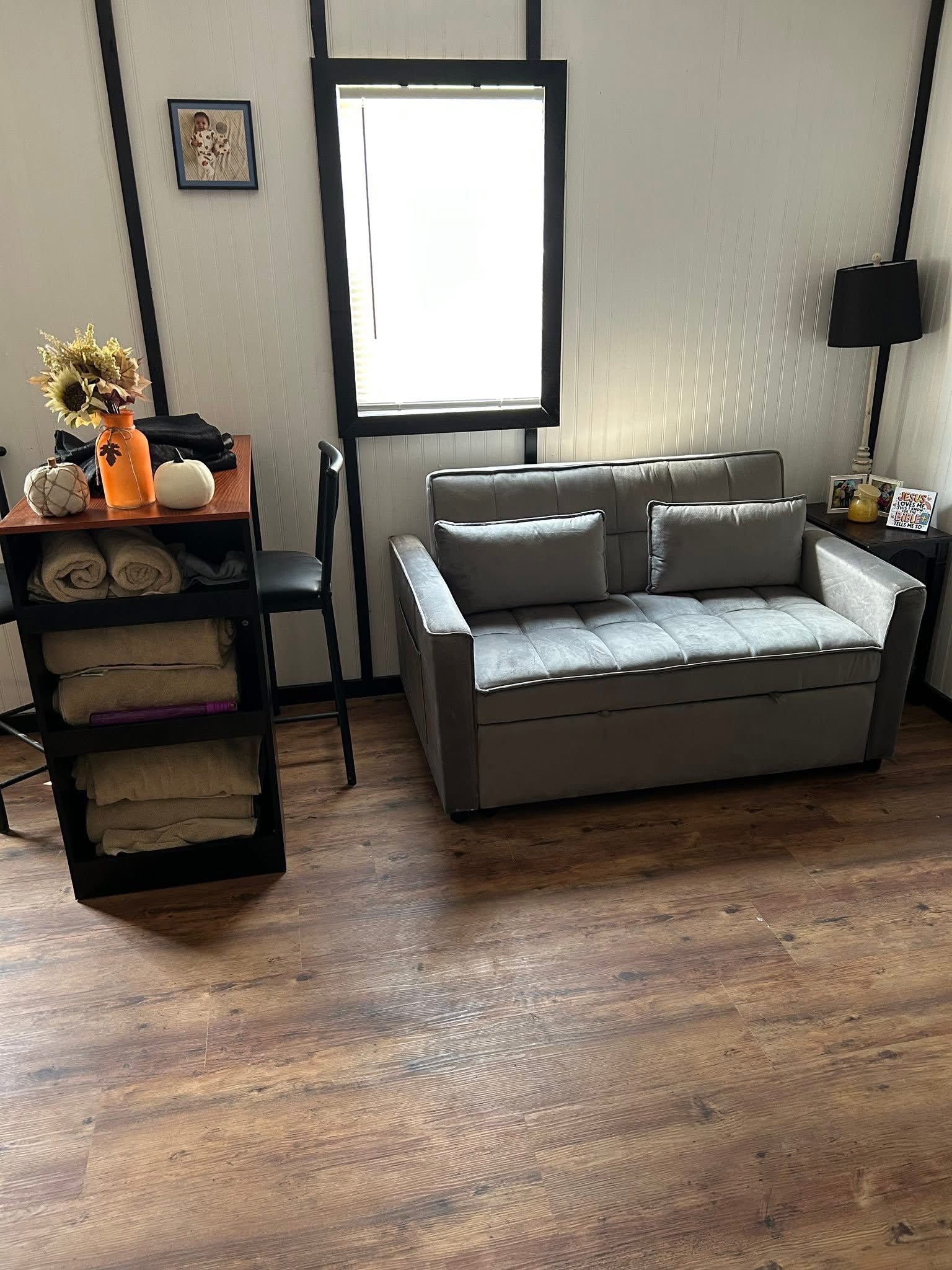 Tiny house living area with loveseat and shelving